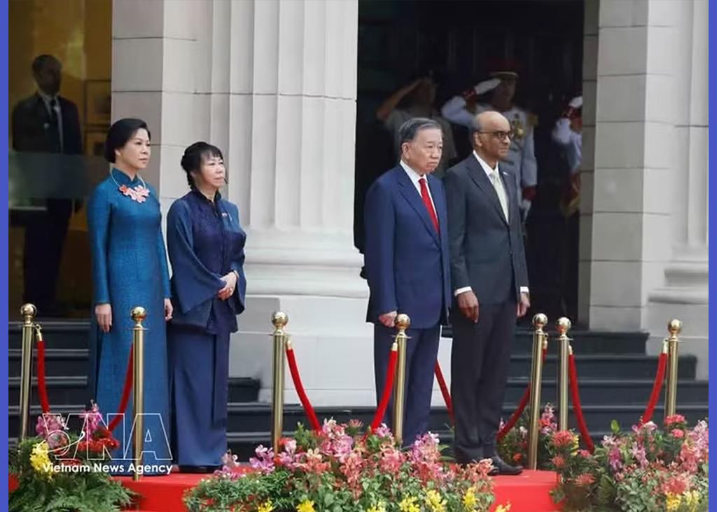 Party General Secretary and State President To Lam and Singaporean President Tharman Shanmugaratnam, together with their spouses, stand on the podium of honour as military bands perform the national anthems of Viet Nam and Singapore at the welcome ceremony on May 29 morning. (Photo: VNA)